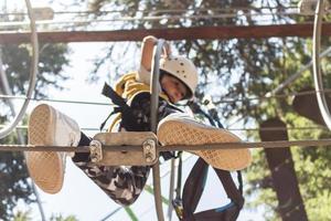 Below view of child getting through obstacles while walking on zip line. photo