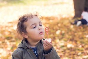 Cute small girl blowing bubbles. photo