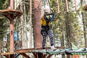 Small kid walking on a rope during canopy tour in nature. photo