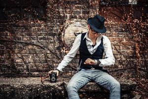 Retro-styled man checking time on wristwatch while sitting outdoors. photo