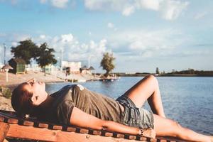 Sie view of woman lying on deck chair at the beach. photo