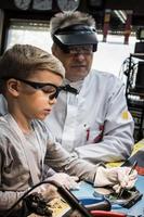 Little boy repairing computer part during IT lesson in science laboratory. photo