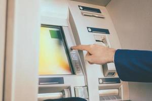 Close-up of man using ATM in the city. photo