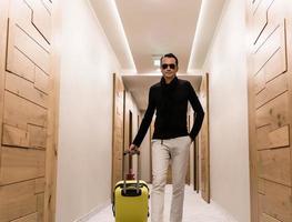 Mid adult  man carrying suitcase while walking through a hallway. photo