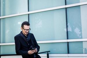 Smiling businessman text messaging on mobile phone. photo