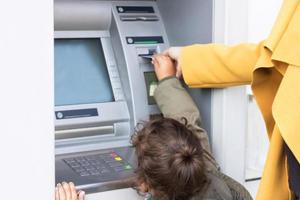 Little girl and her mother withdrawing money form ATM. photo