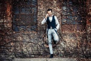 Retro-styled man with sunglasses while leaning on a wall. photo