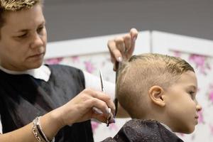 debajo de la vista del peluquero cortando el cabello del niño en el salón. foto