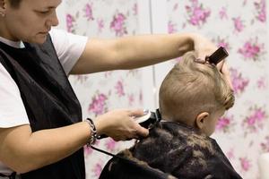Little boy having haircut at barber shop. photo