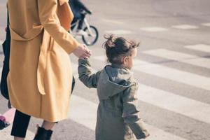 niña cruzando la calle con su madre. foto