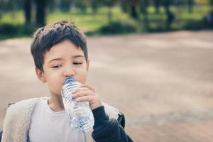 Little boy drinking water form plastic bottle. photo