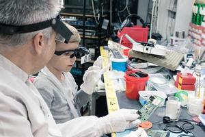 It technician  and little boy examining circuit board in tech laboratory. photo