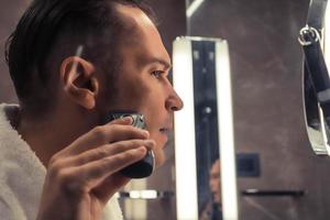 Close-up of man shaving with electric razor. photo