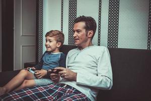 Happy son and father playing video game at home. photo