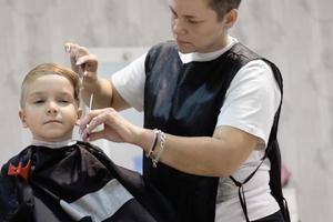 niño pequeño peinándose con un peluquero. foto