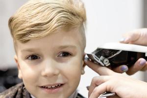 primer plano de niño durante el corte de pelo en el salón. foto