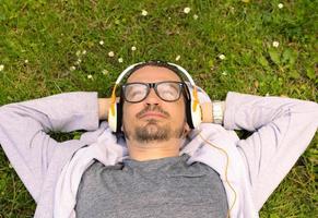 Above view of relaxed man with headphones lying down on grass. photo