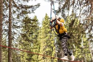 Little boy walking on a zip line while being on canopy tour in the forest. photo