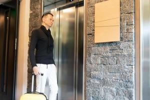hombre adulto medio con maleta esperando el ascensor. foto