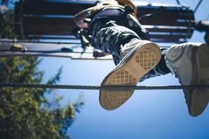 Directly below view of child walking on hanging rope in adventure park. photo