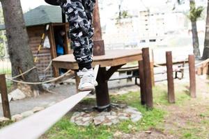 Unrecognizable kid walking on a rope during canopy tour. photo