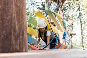 Small boy crawling through obstacles during canopy tour in nature. photo