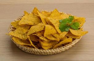 Nachos in a basket on wooden background photo