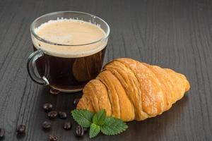 café con croissant sobre fondo de madera foto