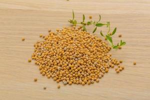 Mustard seeds on wooden background photo