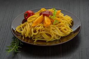 Vegetarian pasta on the plate and wooden background photo