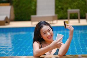 online payment, A teenage girl who swims is using her credit card with her phone to make purchases. online via internet. photo