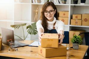 Business owner picking up parcel boxes And use a computer to check online orders to prepare the packaging. pack products to send to customers. photo