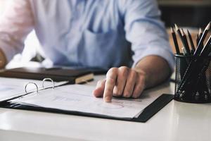 Examining the financial budget, a male auditor is pointing to a file to summarize the company's irregular financial budget. photo