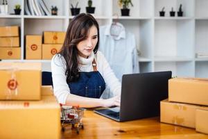 trabajar desde casa. las mujeres felices que venden productos en línea inician una pequeña empresa usando una computadora portátil para calcular los precios y prepararse para el franqueo. foto