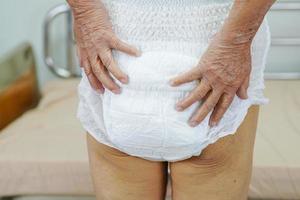 Asian elder senior woman patient wearing adult incontinence diaper pad in hospital. photo