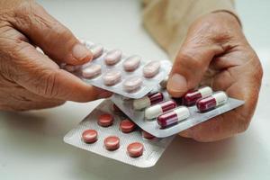 Asian elderly woman holding pill drug in hand, strong healthy medical concept. photo