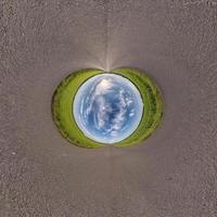 Inversion of blue little planet transformation of spherical panorama 360 degrees. Spherical abstract aerial view on road with awesome beautiful clouds. Curvature of space. photo