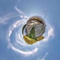 green tiny planet in blue sky with beautiful clouds. Transformation of spherical panorama 360 degrees. Spherical abstract aerial view. Curvature of space. photo