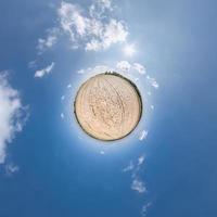 tiny planet transformation of spherical panorama 360 degrees. Spherical abstract aerial view in field with clear sky and awesome beautiful clouds. Curvature of space. photo