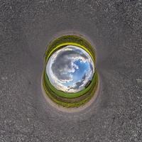 Inversion of blue little planet transformation of spherical panorama 360 degrees. Spherical abstract aerial view on road with awesome beautiful clouds. Curvature of space. photo