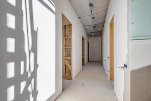 Empty unfurnished corridor room with minimal preparatory repairs. interior with white walls and drywall photo