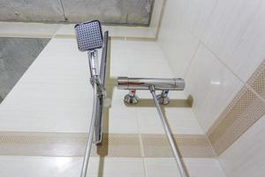 grifo de agua cuadrado con grifo en baño caro. detalle de una cabina de ducha de esquina con accesorio de ducha montado en la pared foto
