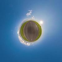 pequeño planeta verde en el cielo azul con hermosas nubes. transformación de panorama esférico 360 grados. vista aérea abstracta esférica. curvatura del espacio. foto