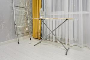 modern iron on ironing board in white room photo