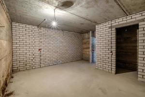 Empty unfurnished basement room with minimal preparatory repairs. interior with white brick walls photo