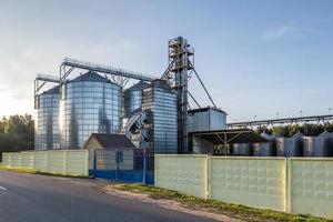 ascensor de granero moderno con silos de plata en la planta de procesamiento y fabricación de productos agrícolas para el procesamiento, secado, limpieza y almacenamiento de productos agrícolas, harina, cereales y granos. foto