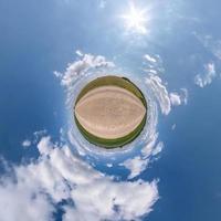 tiny planet in blue sky with sun and beautiful clouds. Transformation of spherical panorama 360 degrees. Spherical abstract aerial view. Curvature of space. photo