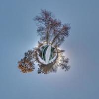 Winter tiny planet in snow covered forest on wooden bridge. transformation of spherical panorama 360 degrees. Spherical abstract aerial view in forest. Curvature of space. photo