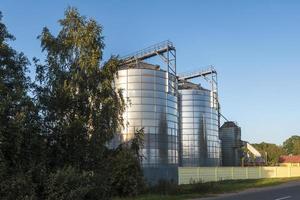 ascensor de granero moderno con silos de plata en la planta de procesamiento y fabricación de productos agrícolas para el procesamiento, secado, limpieza y almacenamiento de productos agrícolas, harina, cereales y granos. foto