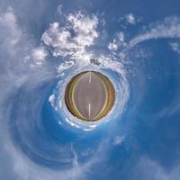 tiny planet in blue sky with beautiful clouds. Transformation of spherical panorama 360 degrees. Spherical abstract aerial view. Curvature of space. photo